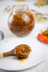 Jerk sauce in a jar with chili peppers on the side.