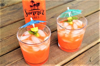 Mango soda in glasses with umbrella, wooden background.