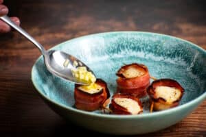 Bacon wrapped scallops in blue dish.