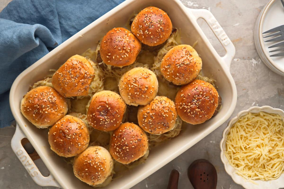 Bison sliders in casserole dish with shredded cheese on the side.