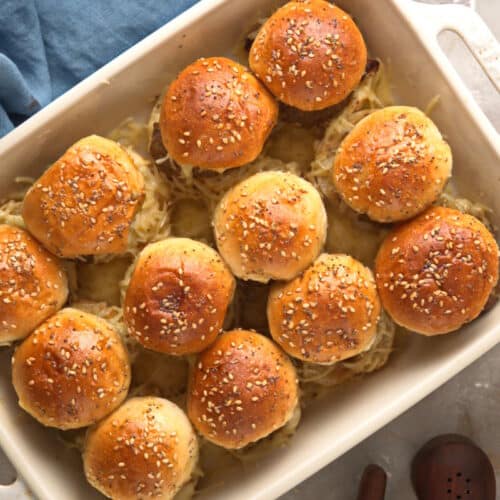 Bison sliders in casserole dish with shredded cheese on the side.