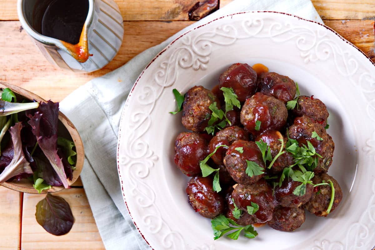 Bison meatballs with BBQ sauce and parsley on white plate.