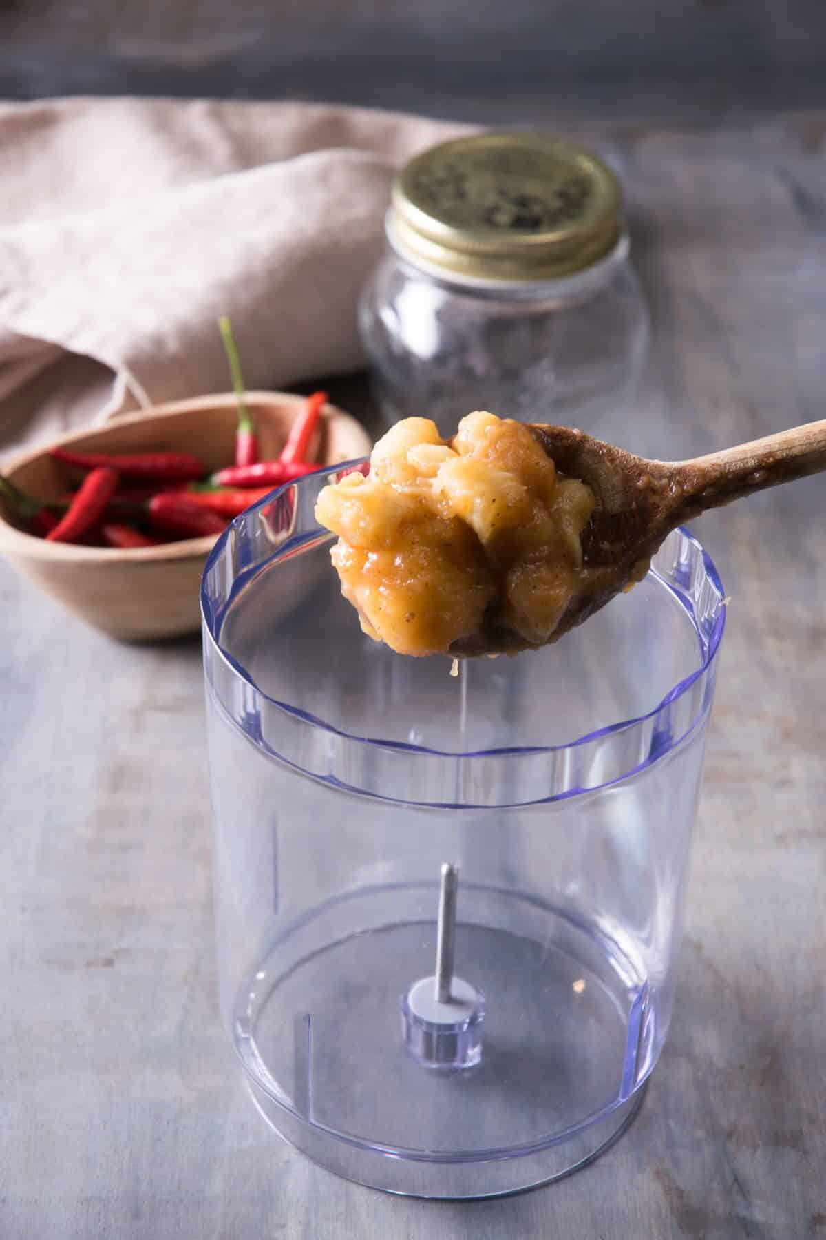 Banana ketchup mixture on a wooden spoon and a blender jar.