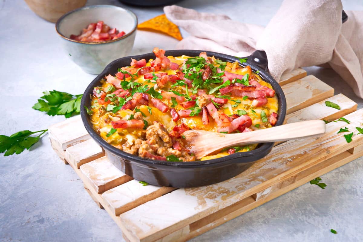 Bison dip in cast iron skillet with a wooden spoon.