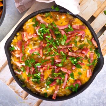 Bison dip in cast iron skillet on wooden board.