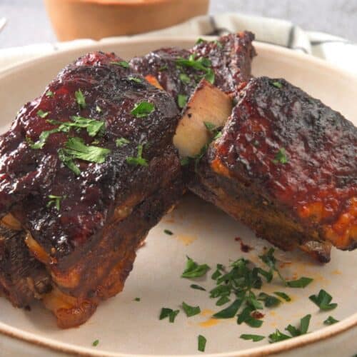 Cooked BBQ bison ribs in white dish.