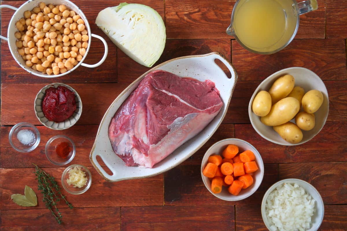 Bison chuck roast and vegetables prepped on wooden background.