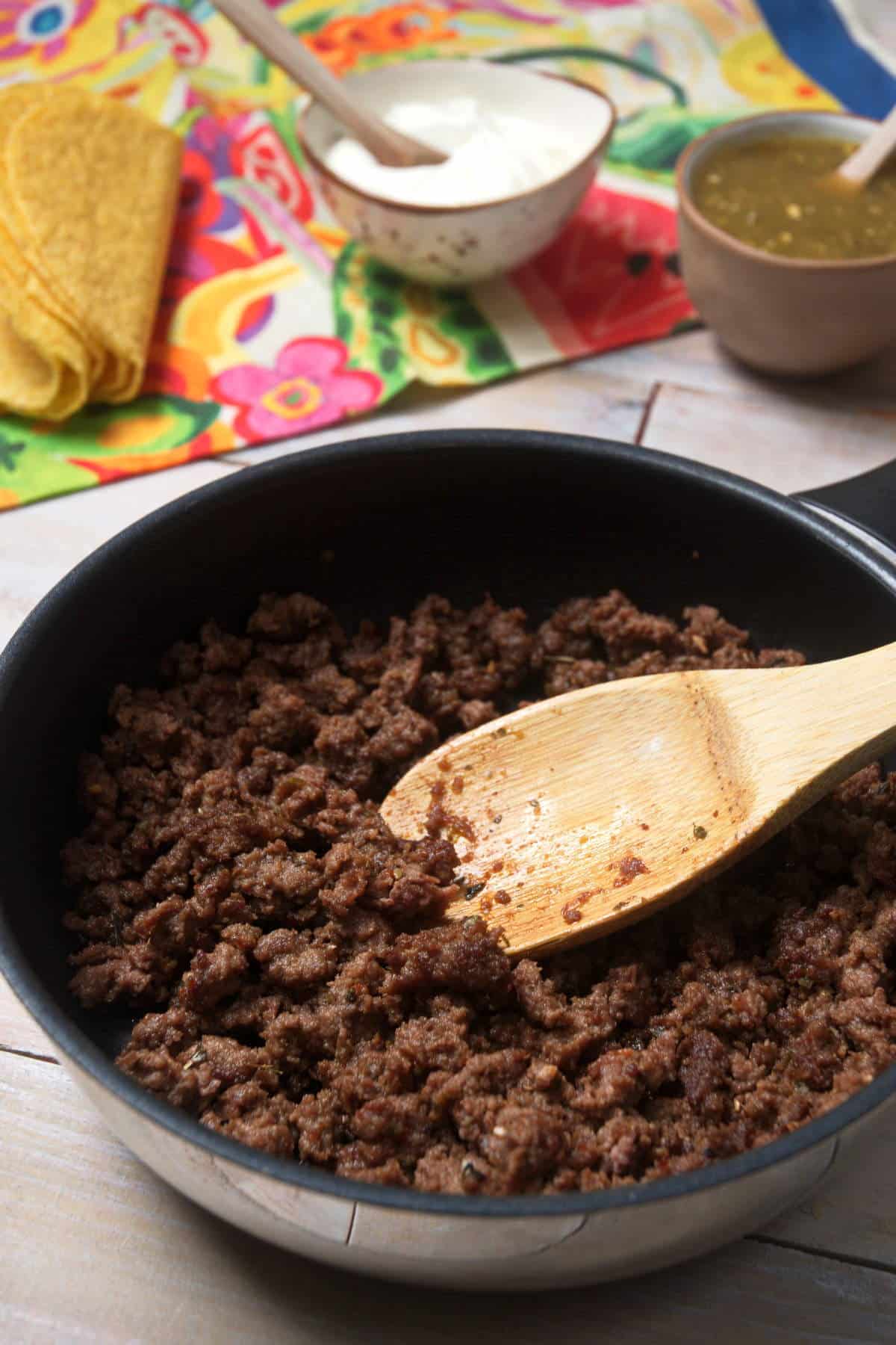 Ground bison in pan with wooden spoon.