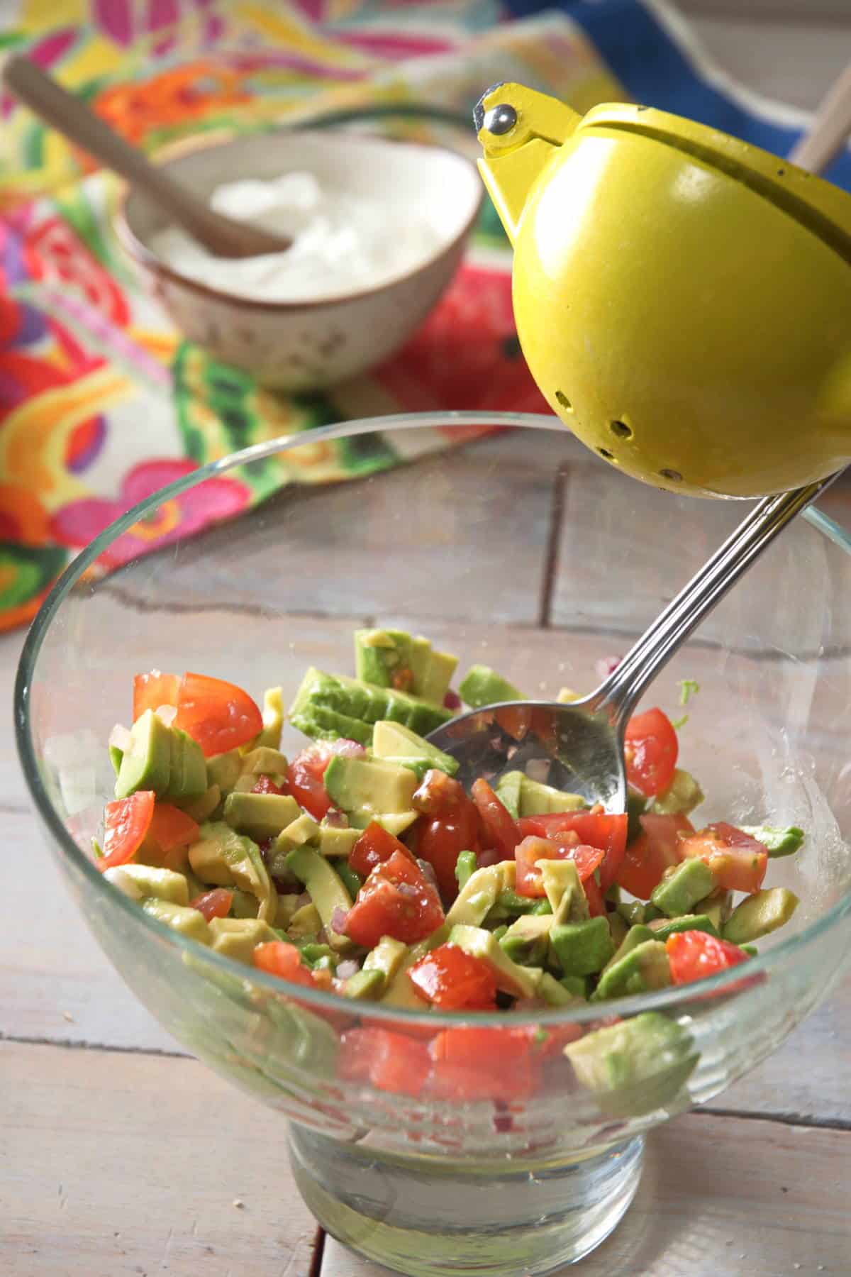 Diced avocado and tomatoes in small glass bowl.