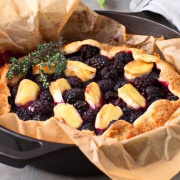 Blackberry galette with brie and thyme in a parchment lined cast iron pan.