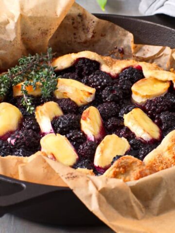 Blackberry galette with brie and thyme in a parchment lined cast iron pan.