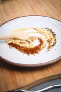 Blackening spices on a plate with a wooden spoon.