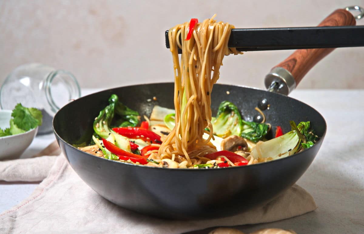 Bok choy stir fry with chow mein noodles and chopsticks in pan.