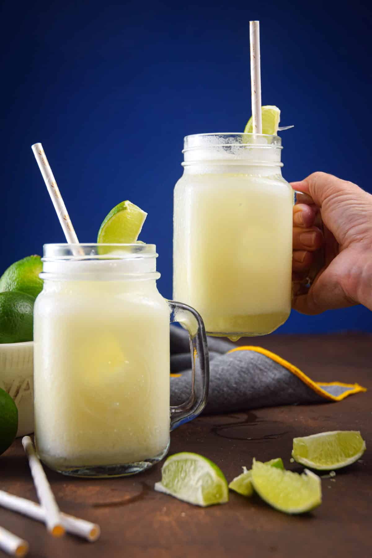 Brazilian lemonade in glass jars with lime wedges and paper straws.