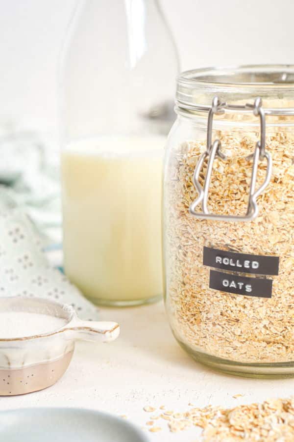 Rolled oats in a jar with a bottle of milk, white background.