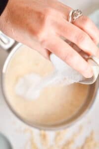 Oats in a pot with sugar, white background.