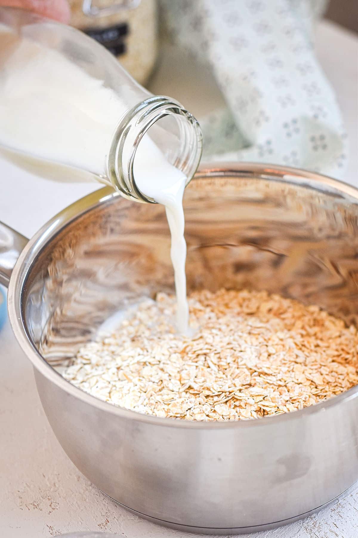 Milk pouring into saucepan with oatmeal.