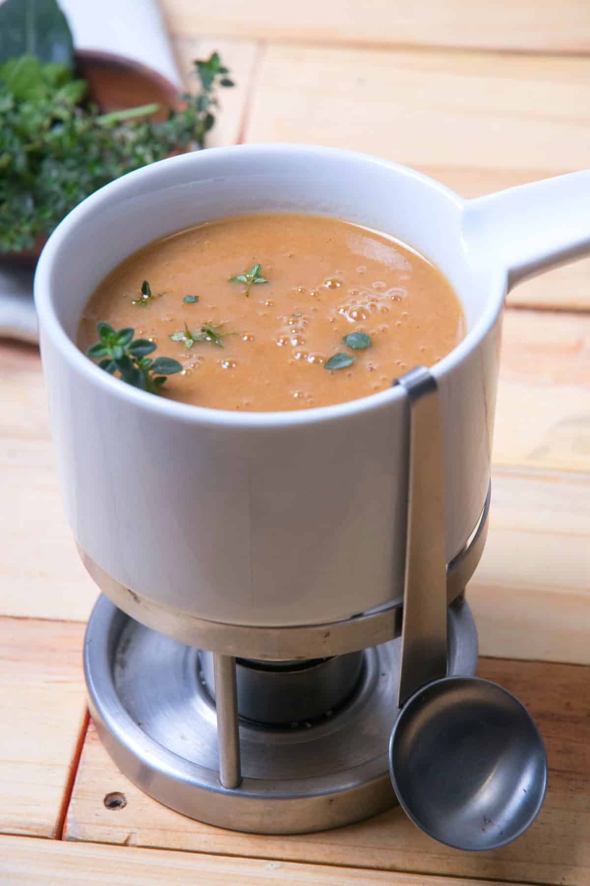 Brown gravy in a gravy warmer on wooden background.