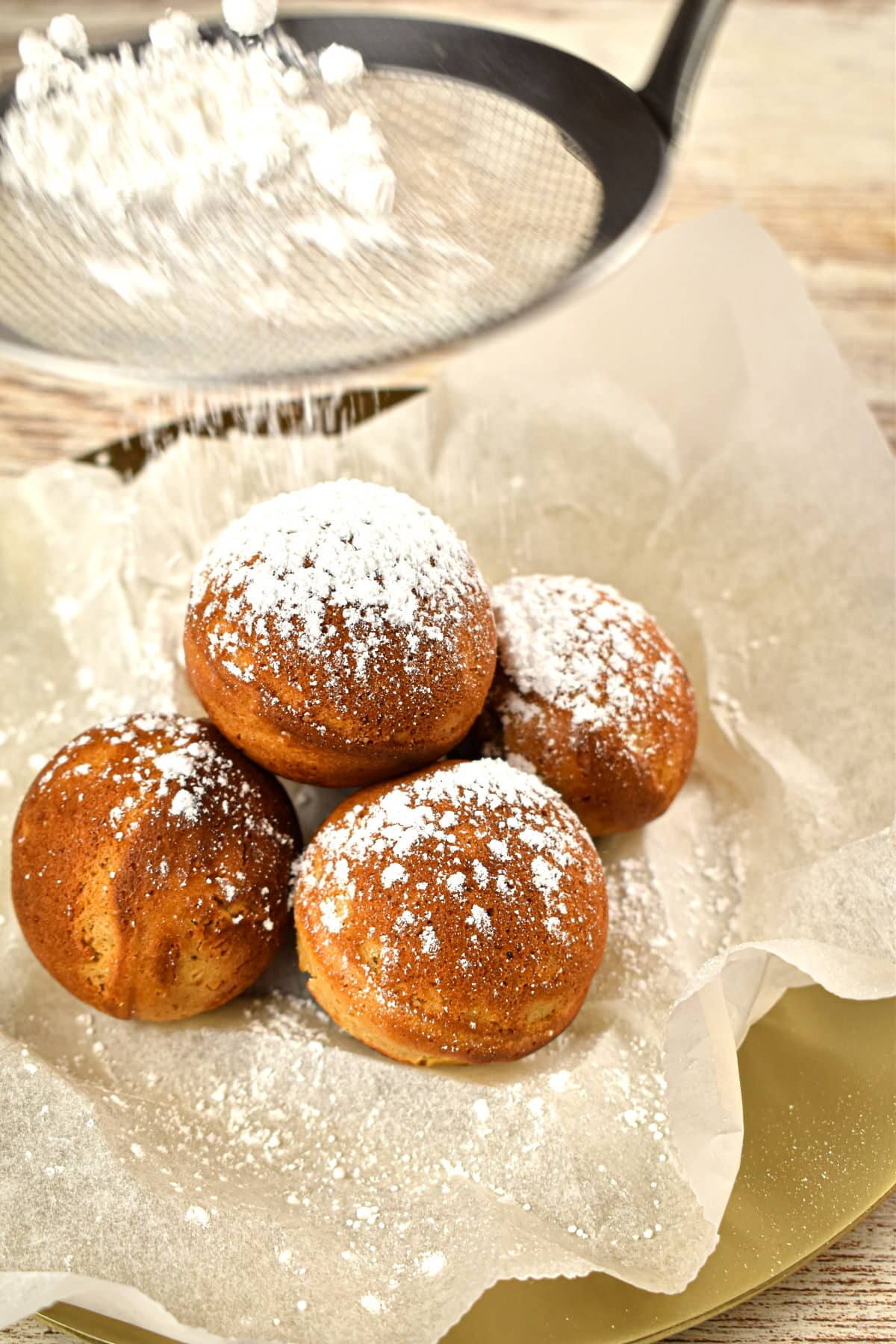 Gingerbread cake balls on parchment, covered in powdered sugar.