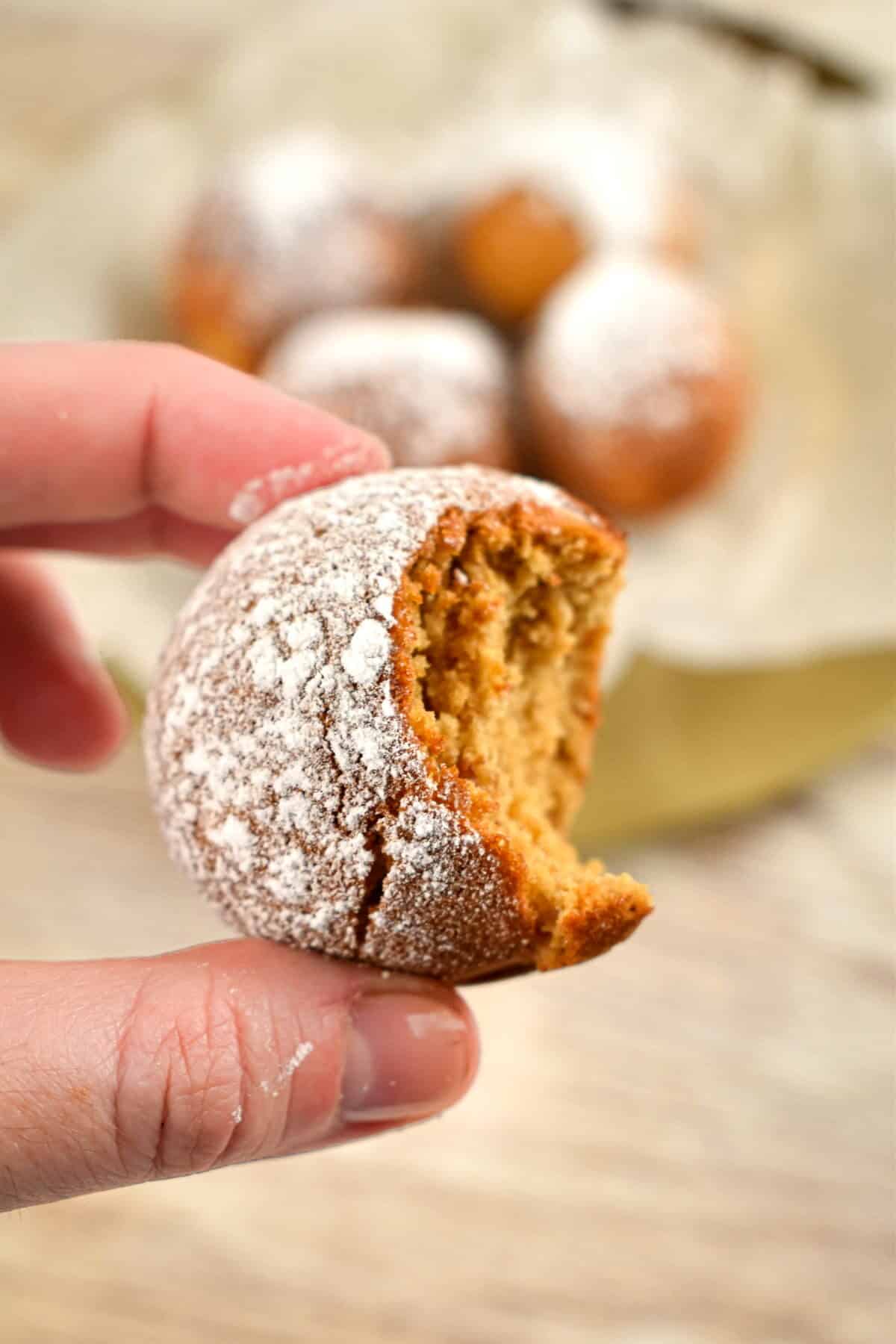 A hand holding a gingerbread cake pop that has been bitten into.