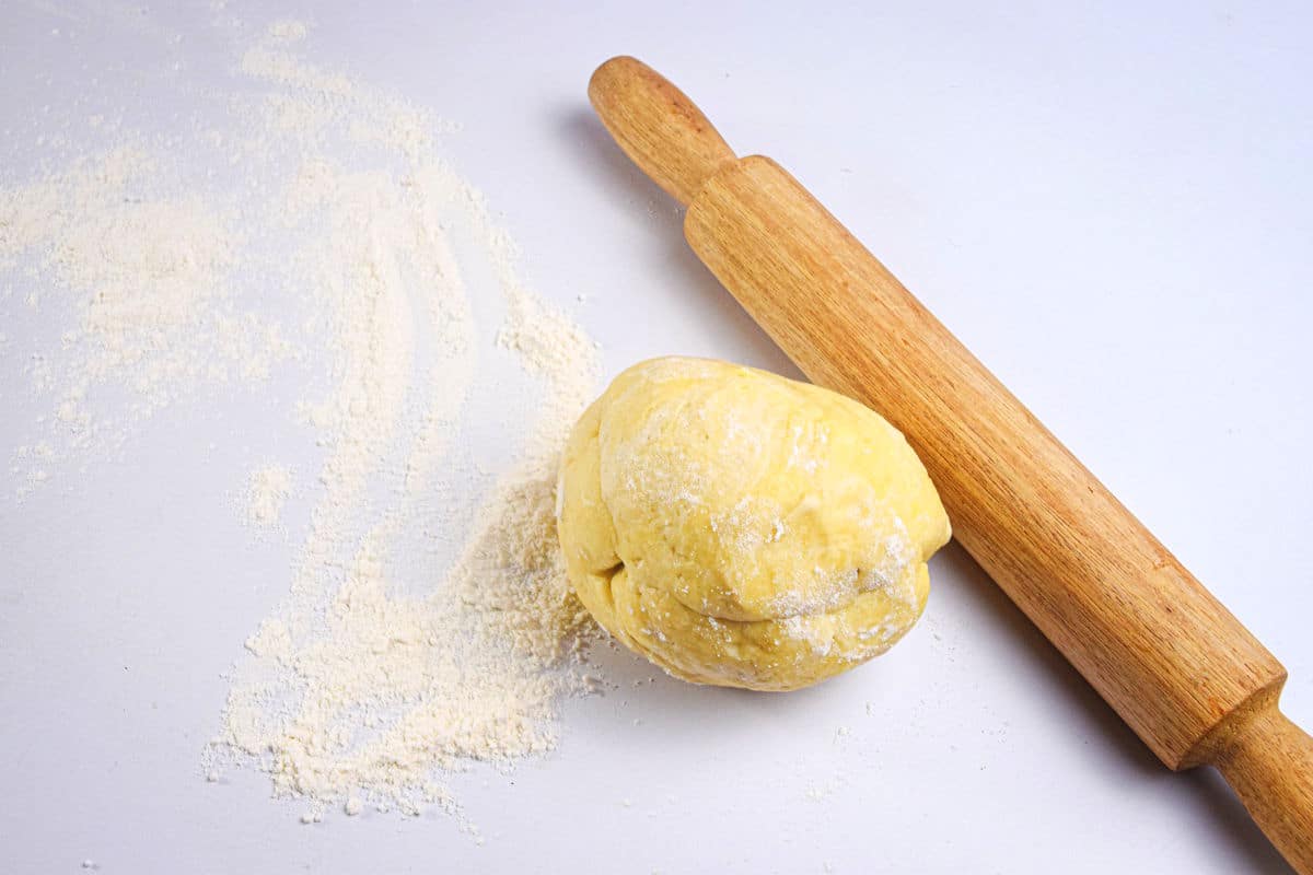 Pastry dough and wooden rolling pin on counter.