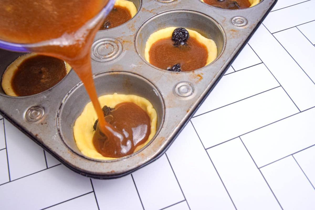 Unbaked butter tarts in muffin tin.