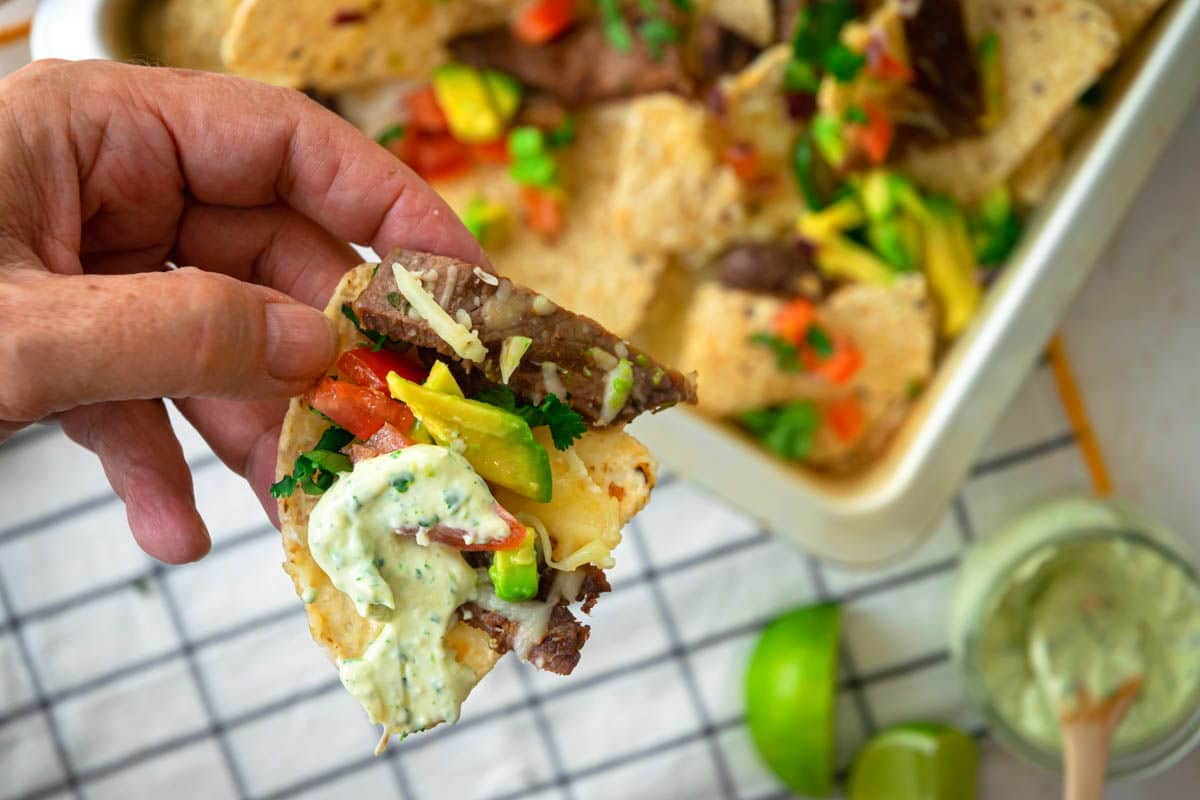 Carne asada nachos in a pan, cilantro dip on the side.