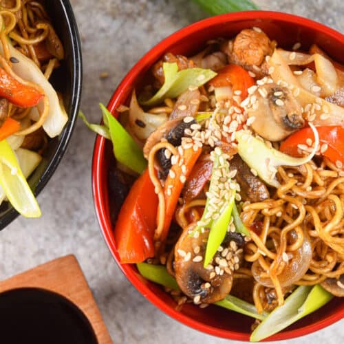 Chicken lo mein noodles in red and black bowls with chop sticks.
