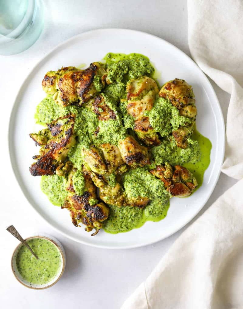 Chicken coated in a cilantro sauce on a white plate.