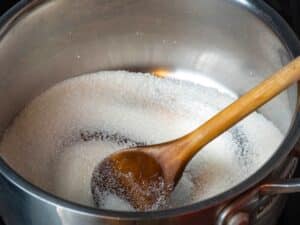 Sugar in saucepan with wooden spoons.