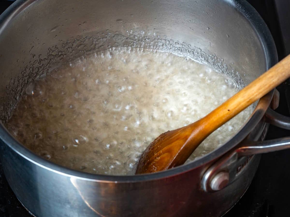 Melted sugar in saucepan with wooden spoon.