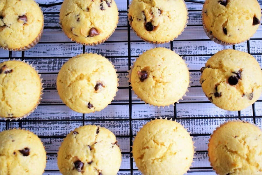 Chocolate Chip Orange Zest Muffins on a baking rack, white wooden background.