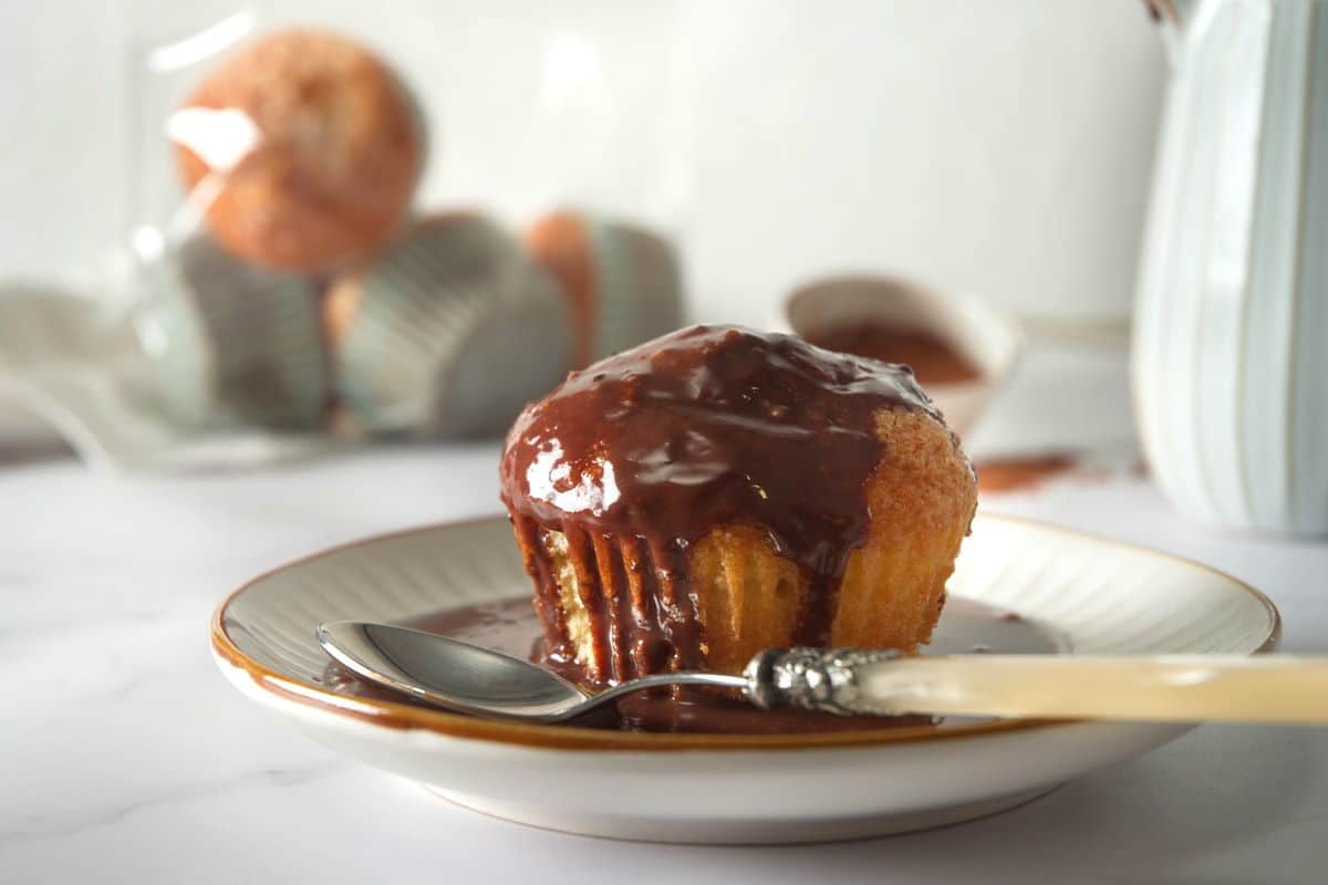 Chocolate gravy over a muffin on a small plate.