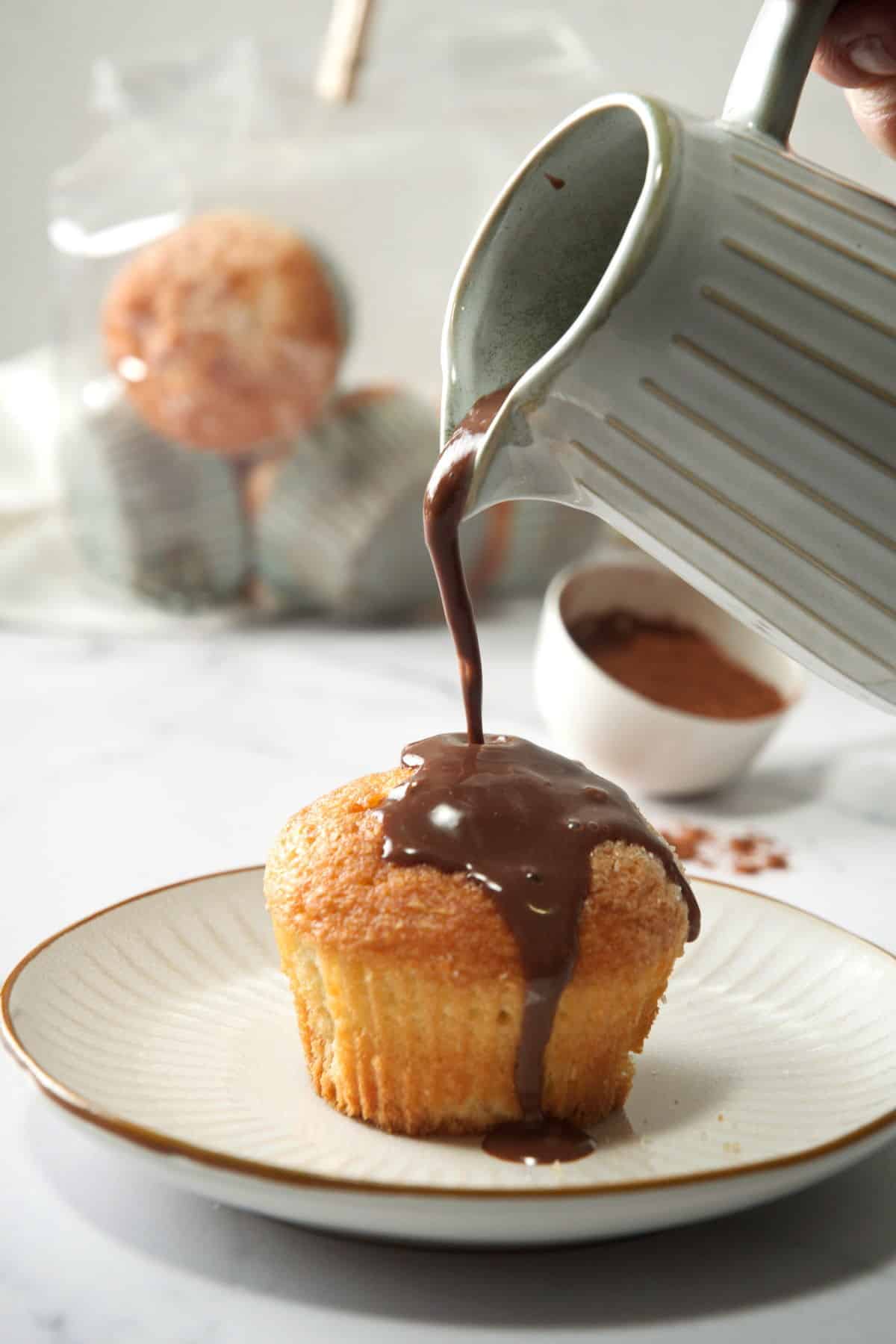 Chocolate gravy pouring over a muffin on a small plate.