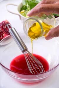 Pomegranate dressing in a small bowl with a whisk.