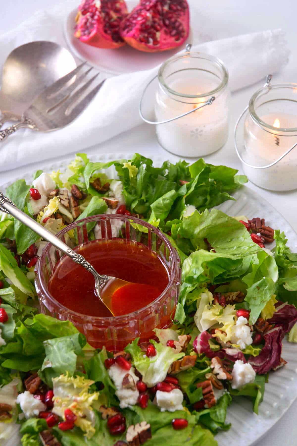 Christmas wreath salad on a large serving plate, white candles in the background.