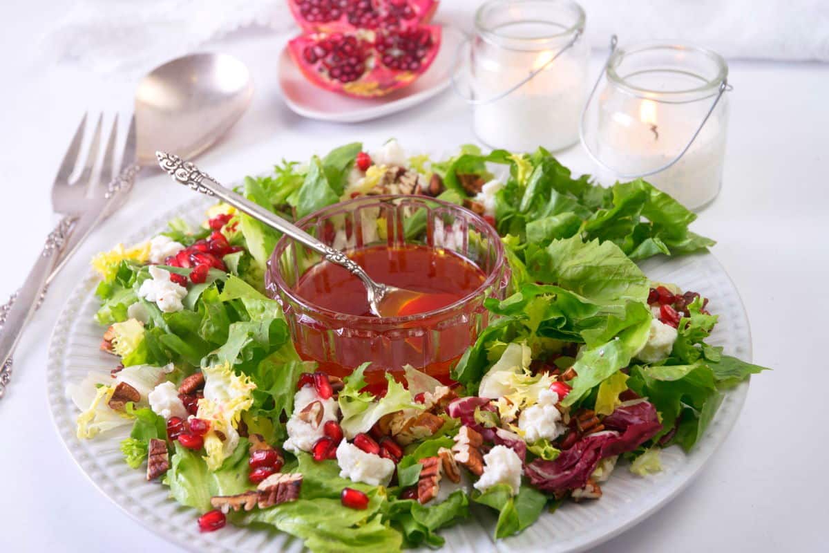 Christmas wreath salad on a large serving plate, white candles on the side.