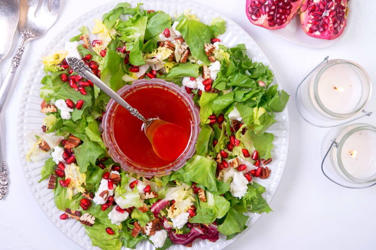 Christmas wreath salad on a large serving plate, white candles on the side.