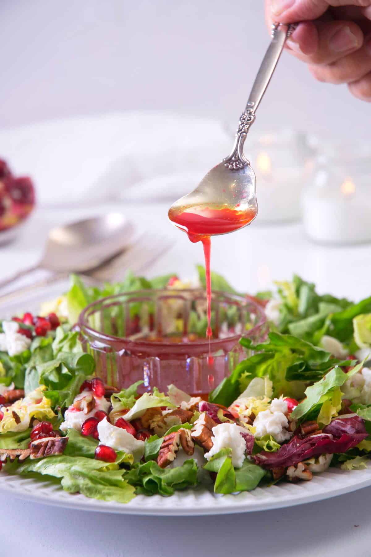 Christmas salad on a large serving plate with pomegranate dressing drizzling over.
