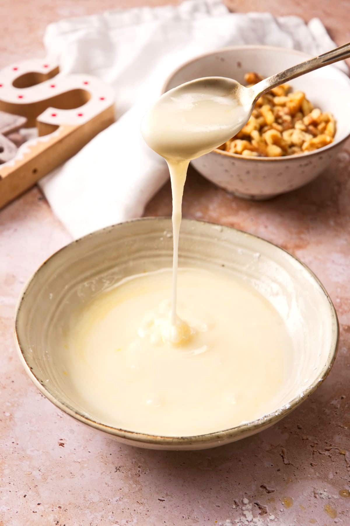 Christmas bundt cake icing in bowl, drizzling from spoon.