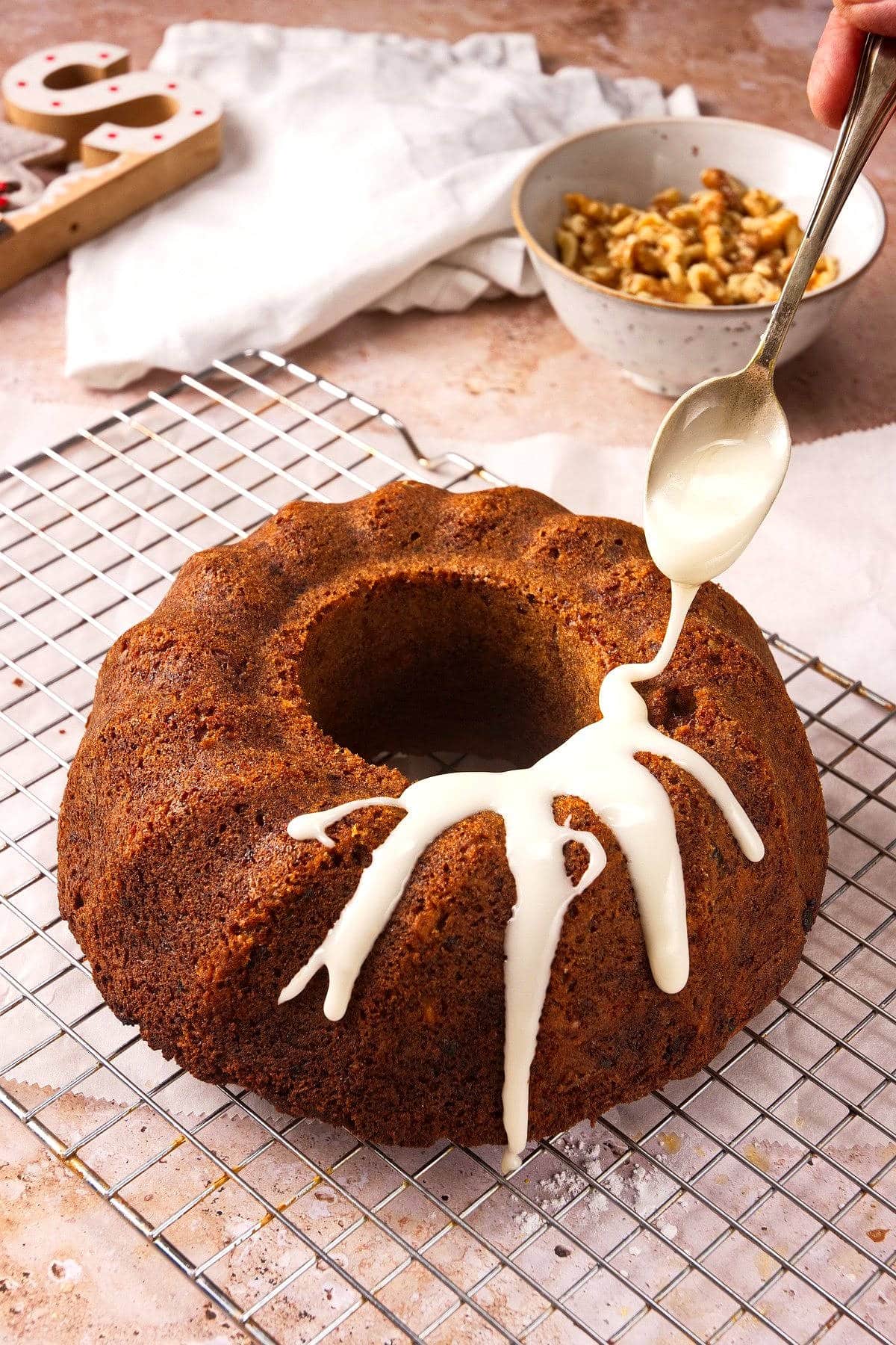 Icing drizzling from spoon over bundt cake.
