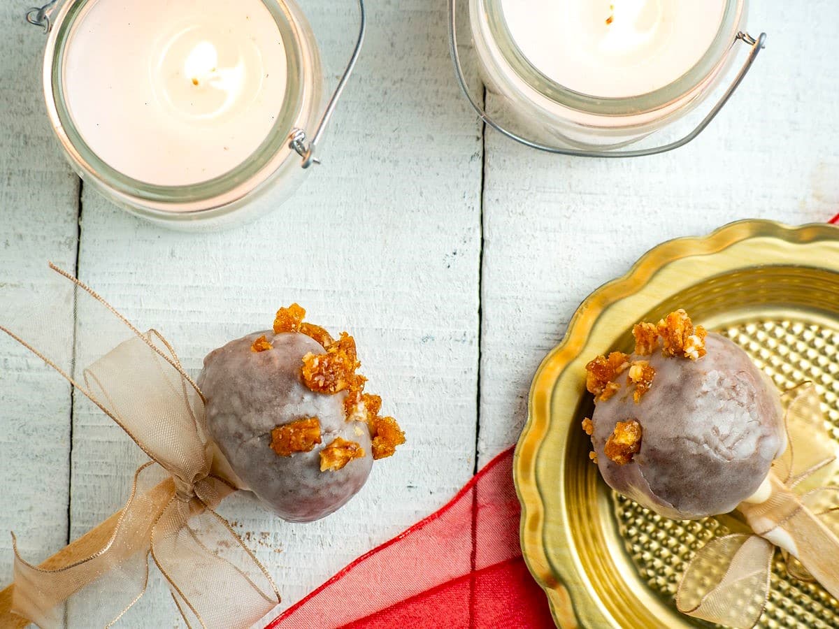 Christmas spice cake pops with beige ribbons and white candles on white wooden background.