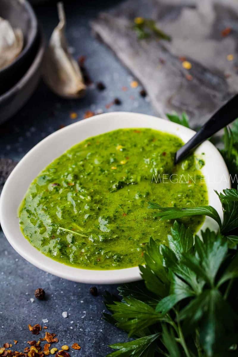 Cilantro chimichurri sauce in a white bowl with small black spoon.