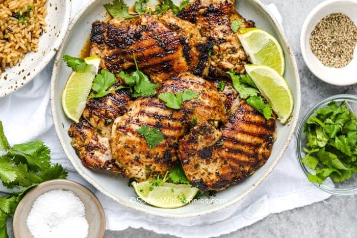 Grilled chicken breast with lime and cilantro on white plate.