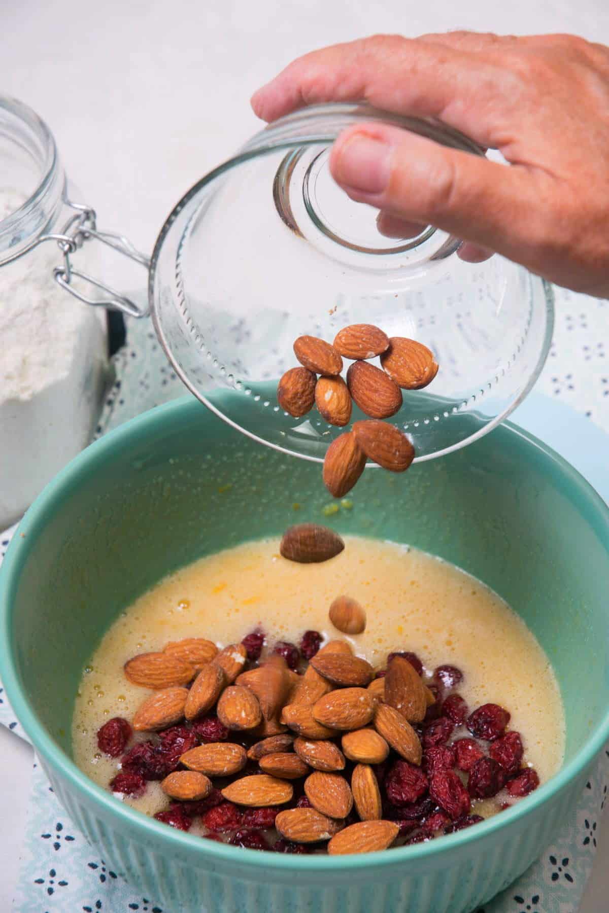 Almonds, cranberries and biscotti wet ingredients in green bowl.
