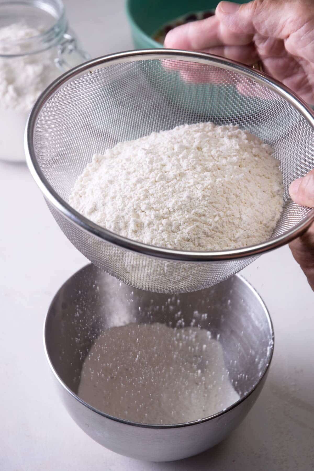 Flour in a sifter and metal bowl.