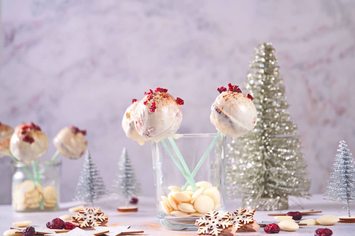 Cranberry white chocolate cake pops in jar with Christmas decorations.