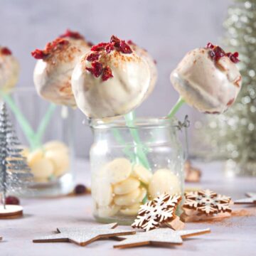 Cranberry white chocolate cake pops in jar with Christmas decorations.