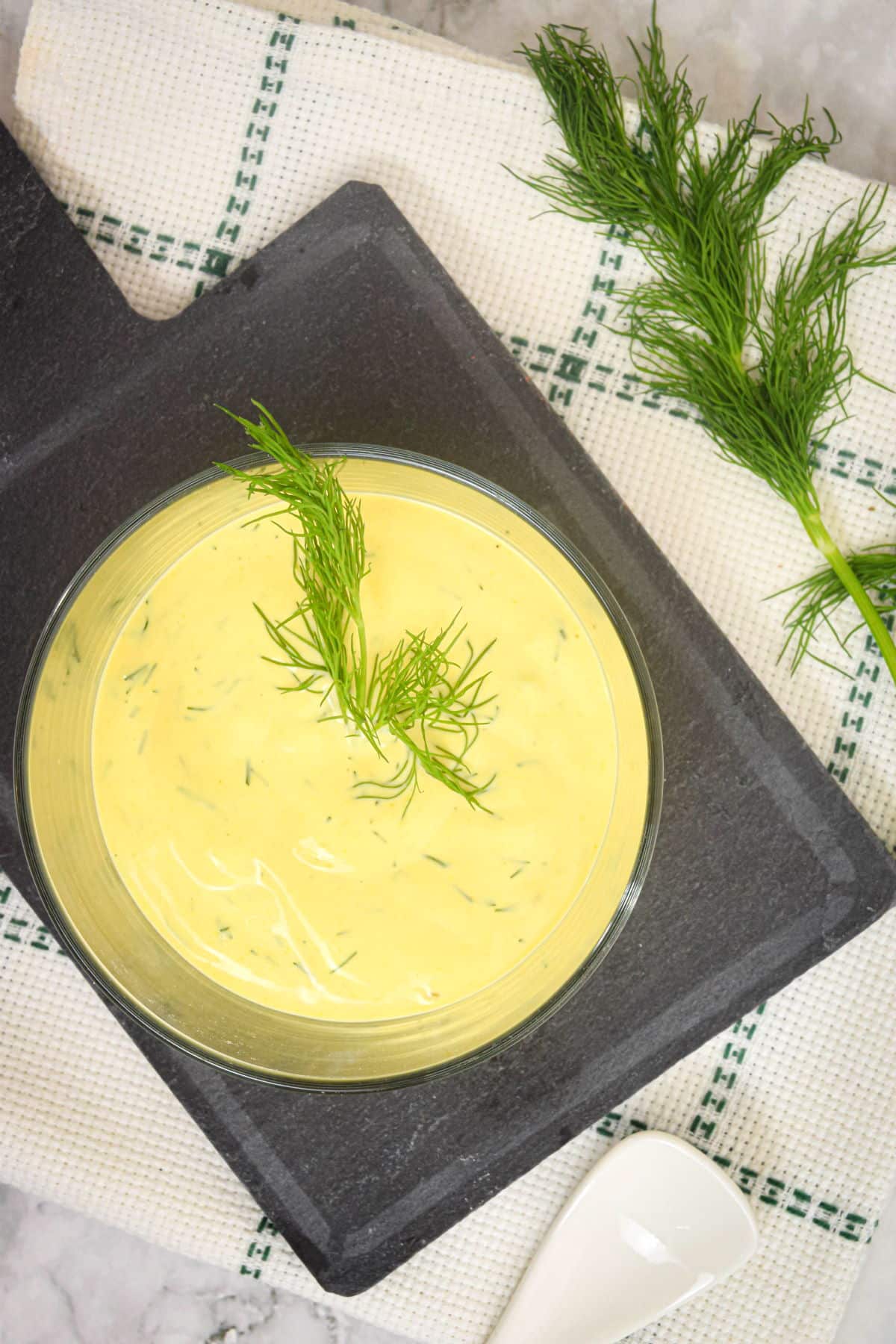 Dill dip in a glass serving dish with fresh dill sprigs.
