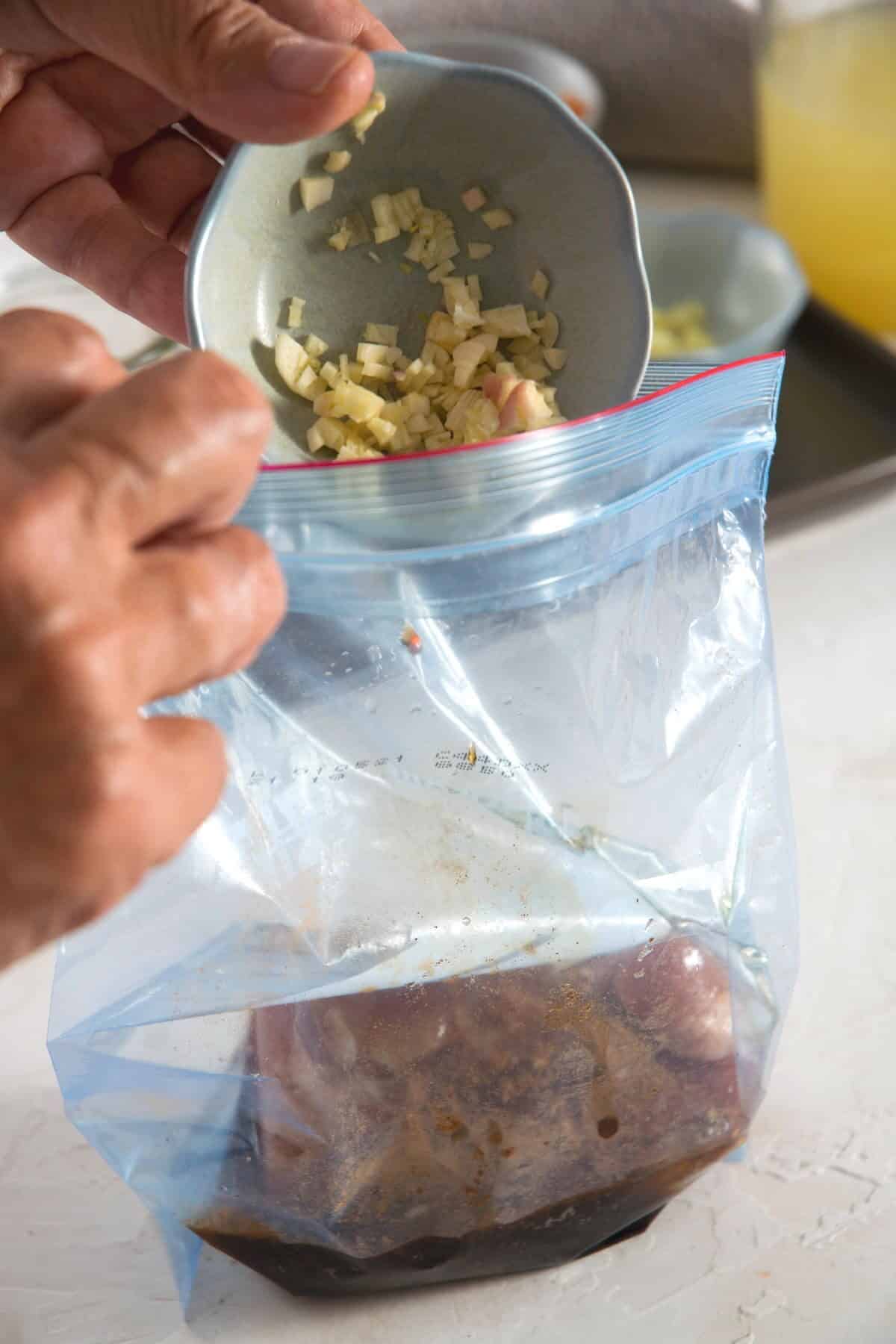 A ziptop bag with pork tenderloin, garlic and marinade.